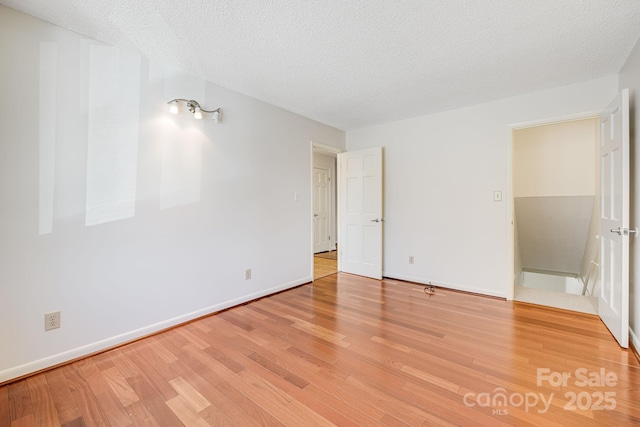 unfurnished bedroom featuring a textured ceiling, light wood-type flooring, and baseboards