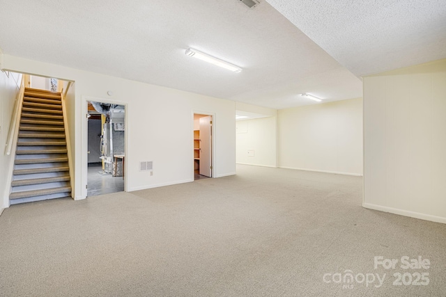 finished basement with visible vents, carpet, stairs, and a textured ceiling