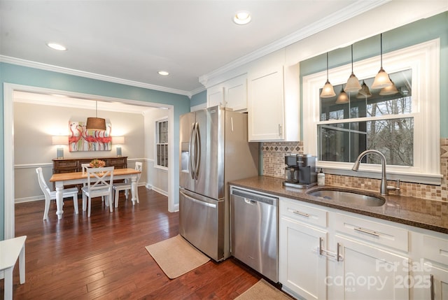 kitchen with dark wood finished floors, dark stone countertops, stainless steel appliances, white cabinetry, and a sink