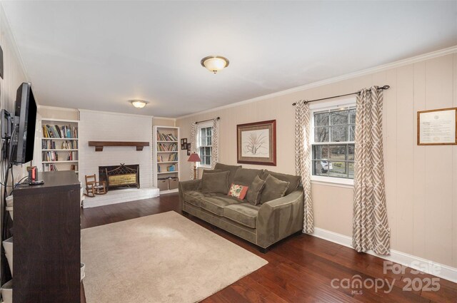 living room featuring baseboards, a fireplace, dark wood finished floors, and crown molding