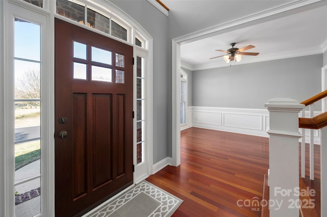 foyer featuring stairs, ornamental molding, wainscoting, dark wood-style floors, and plenty of natural light