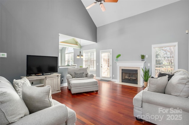 living area with baseboards, high vaulted ceiling, dark wood finished floors, a fireplace with flush hearth, and ceiling fan