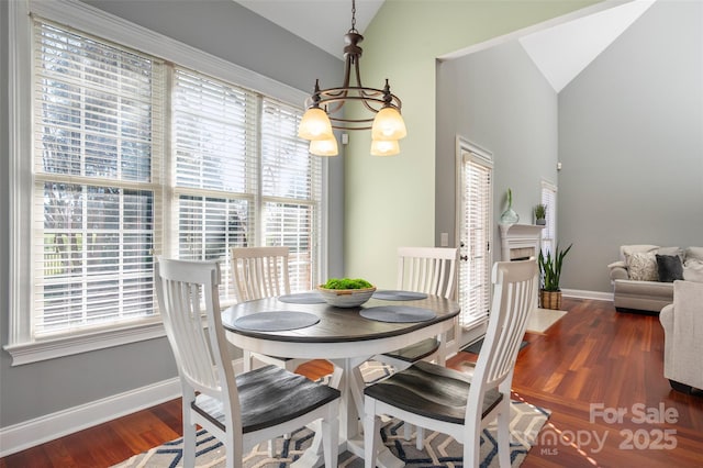 dining space featuring an inviting chandelier, vaulted ceiling, wood finished floors, and baseboards