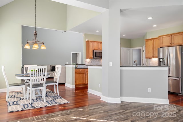 kitchen with baseboards, decorative backsplash, dark wood-style flooring, appliances with stainless steel finishes, and a sink