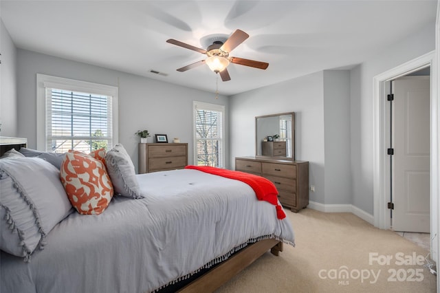 bedroom with visible vents, light carpet, multiple windows, and baseboards