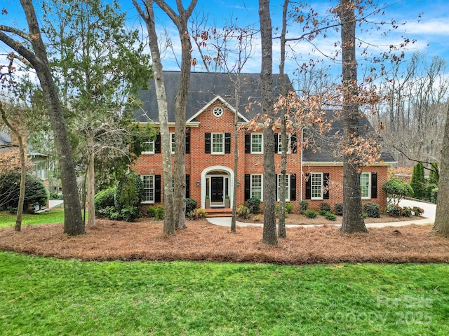 georgian-style home with a front lawn and brick siding