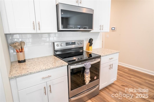 kitchen with appliances with stainless steel finishes, white cabinetry, light wood-style flooring, and tasteful backsplash