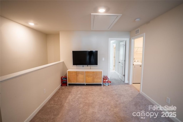 unfurnished living room featuring visible vents, baseboards, attic access, carpet, and washer / dryer