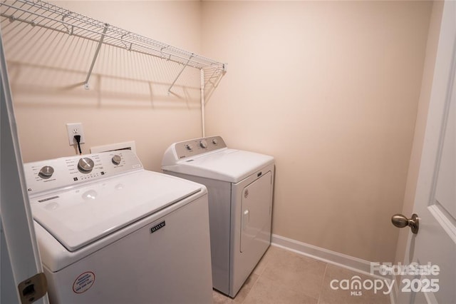 laundry room with light tile patterned floors, laundry area, washing machine and dryer, and baseboards