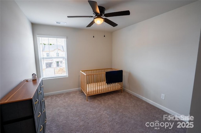 unfurnished bedroom featuring carpet floors, visible vents, a ceiling fan, a nursery area, and baseboards