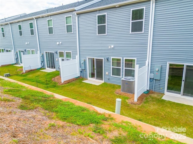 rear view of property with a yard, fence, and central air condition unit