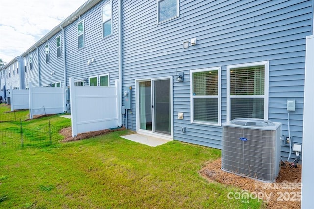 back of house with central AC unit, a lawn, and fence