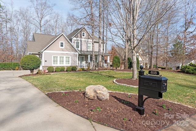 view of front facade featuring driveway, a standing seam roof, a porch, and a front yard