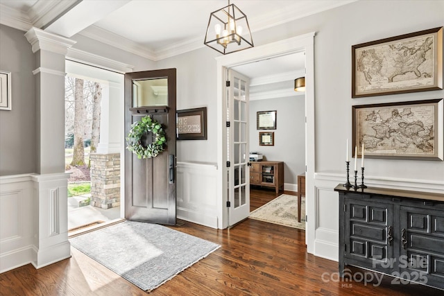 entrance foyer with a wainscoted wall, decorative columns, a decorative wall, ornamental molding, and dark wood-type flooring