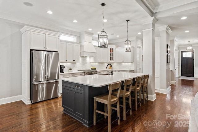 kitchen featuring light countertops, custom range hood, stove, freestanding refrigerator, and white cabinets