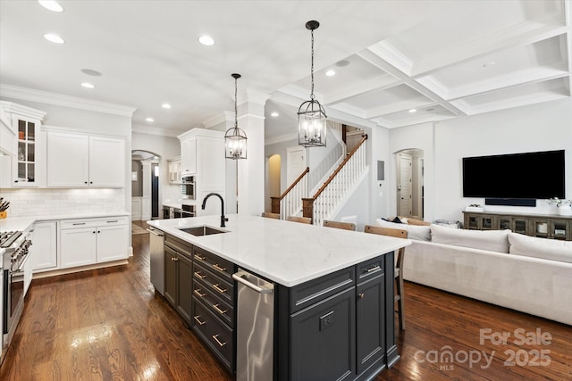 kitchen with arched walkways, white cabinets, and a sink