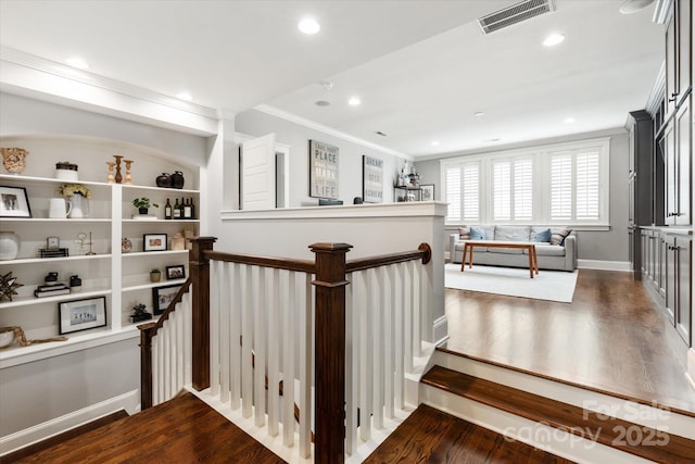 hall featuring recessed lighting, dark wood-style flooring, an upstairs landing, visible vents, and crown molding