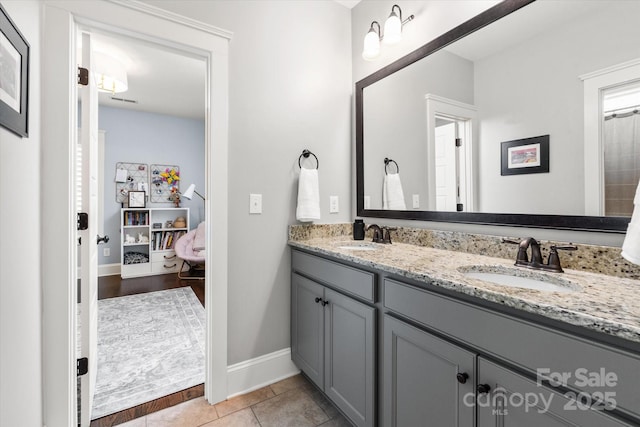 ensuite bathroom with connected bathroom, tile patterned floors, a sink, and double vanity