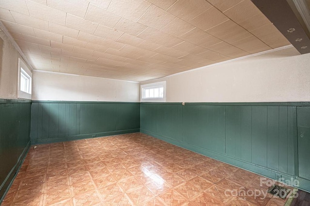 unfurnished room with a wainscoted wall, ornamental molding, and tile patterned floors