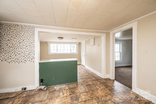 spare room with plenty of natural light, visible vents, ornamental molding, and baseboards