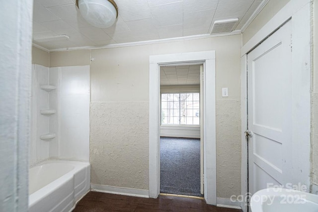 full bath with a textured wall, wood finished floors, visible vents, baseboards, and shower / bathing tub combination