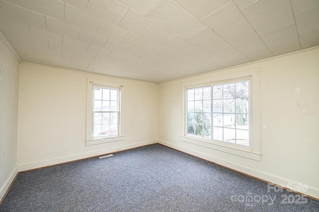 empty room with visible vents, baseboards, and dark colored carpet