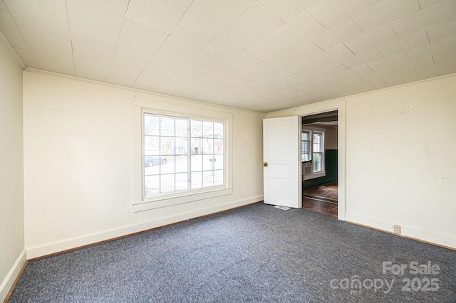 spare room with dark colored carpet and baseboards