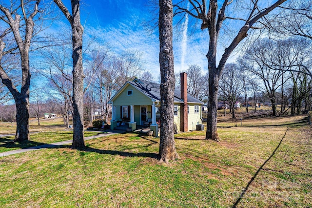 view of front of house with covered porch, a chimney, and a front yard