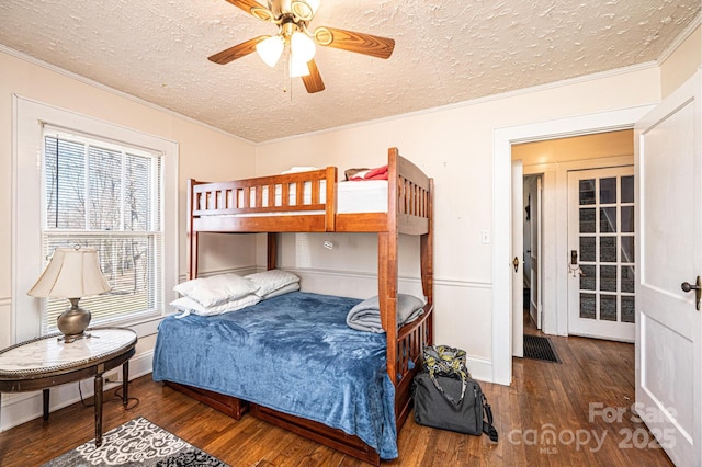 bedroom featuring a textured ceiling, ornamental molding, wood finished floors, and a ceiling fan