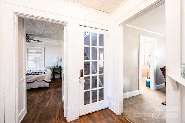 entryway featuring a textured ceiling, ceiling fan, wood finished floors, baseboards, and crown molding