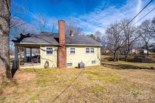 back of house with a lawn, a patio, a chimney, a trampoline, and central air condition unit