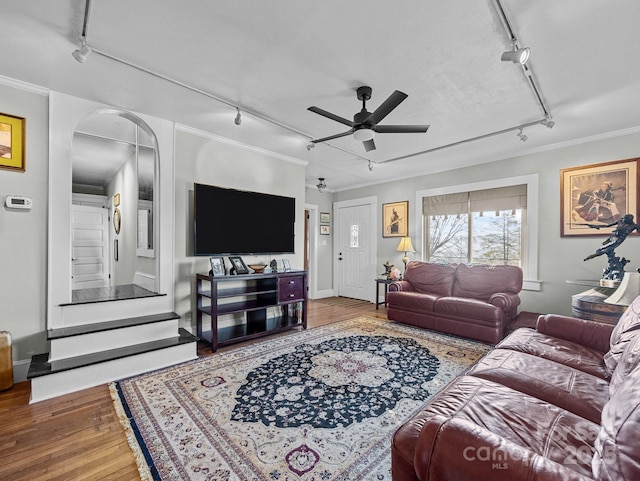 living room with a ceiling fan, wood finished floors, arched walkways, ornamental molding, and rail lighting