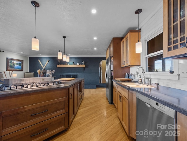 kitchen featuring light wood-type flooring, a sink, dark countertops, appliances with stainless steel finishes, and glass insert cabinets