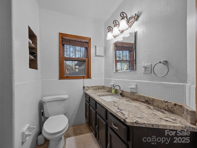 bathroom featuring vanity, tile walls, toilet, and wainscoting