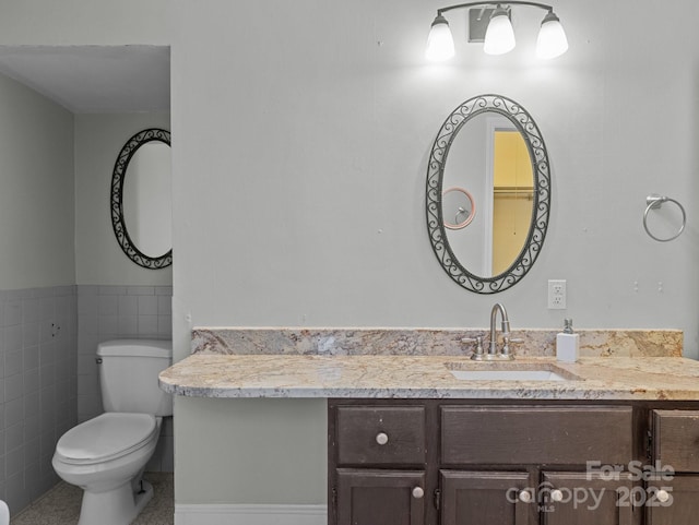 bathroom featuring vanity, tile walls, toilet, and wainscoting