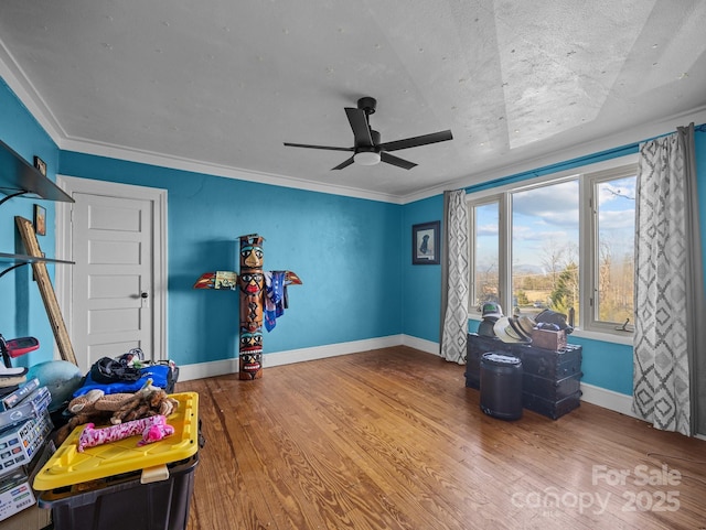 interior space featuring crown molding, wood finished floors, baseboards, and ceiling fan