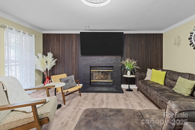 living room with baseboards, a brick fireplace, wood finished floors, and crown molding