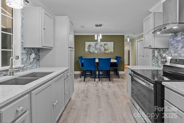 kitchen featuring wall chimney exhaust hood, crown molding, stainless steel electric stove, and a sink