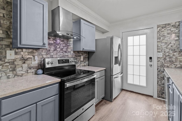 kitchen featuring wall chimney exhaust hood, ornamental molding, gray cabinets, and stainless steel appliances