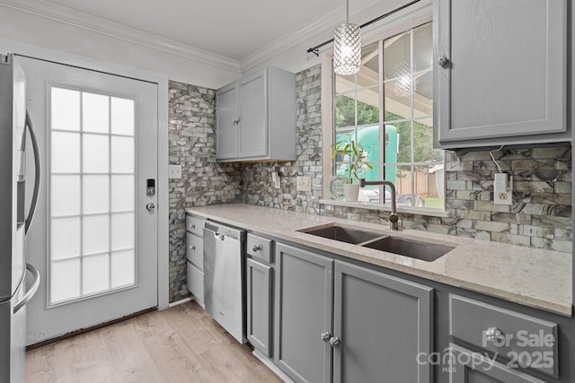 kitchen featuring decorative backsplash, appliances with stainless steel finishes, gray cabinets, crown molding, and a sink