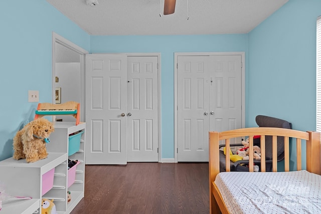 bedroom featuring multiple closets, a ceiling fan, a textured ceiling, and dark wood-style floors