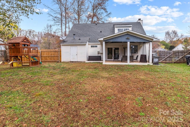 back of house with a playground, a lawn, a patio area, and a fenced backyard