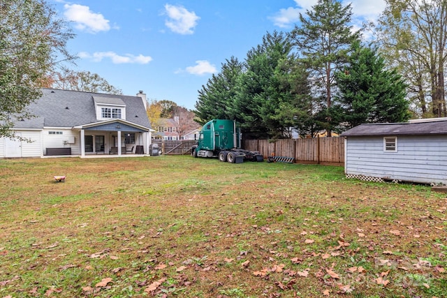 view of yard with a patio area, a fenced backyard, a shed, and an outbuilding