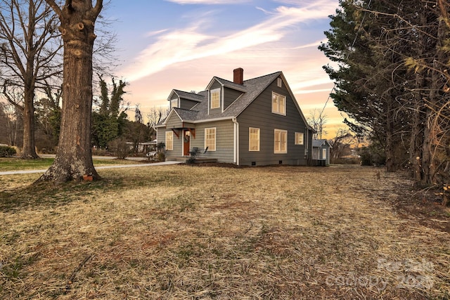 view of front facade with roof with shingles, a front lawn, and a chimney