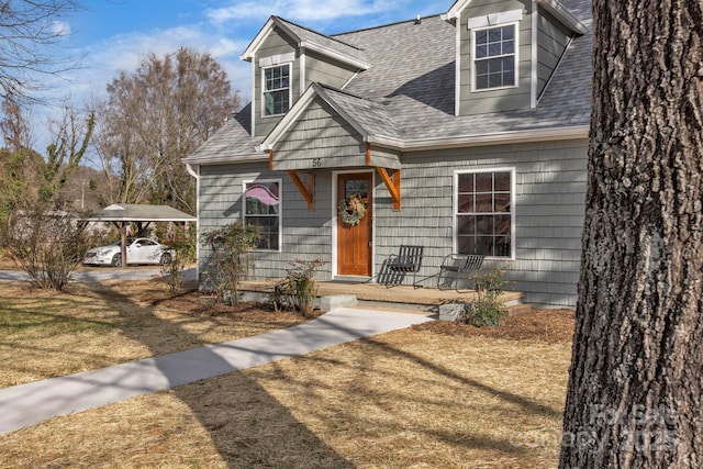 cape cod house with a carport, a shingled roof, and a front lawn