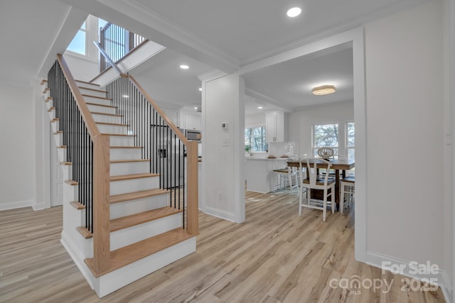 stairway featuring ornamental molding, baseboards, and wood finished floors