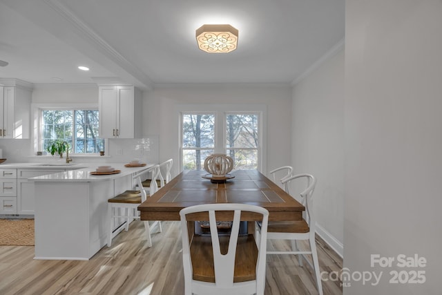 dining area with baseboards, light wood finished floors, and crown molding