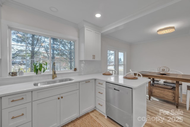 kitchen with light countertops, stainless steel dishwasher, a sink, and crown molding