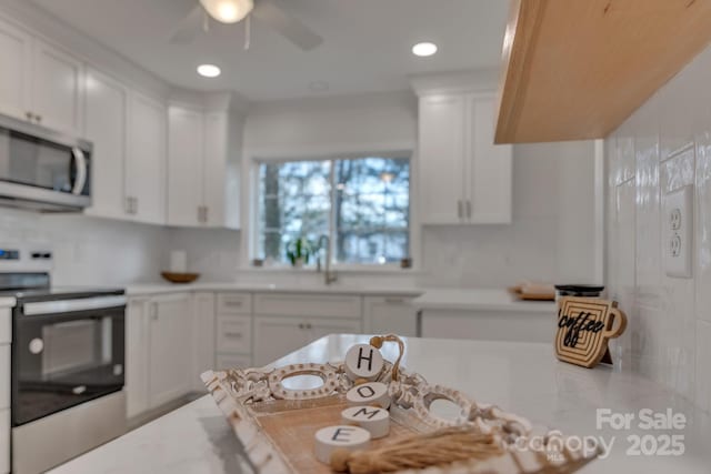 kitchen with white cabinets, stainless steel appliances, a sink, and light countertops