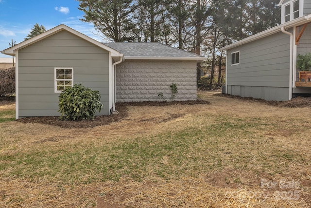 view of property exterior featuring a shingled roof and a yard